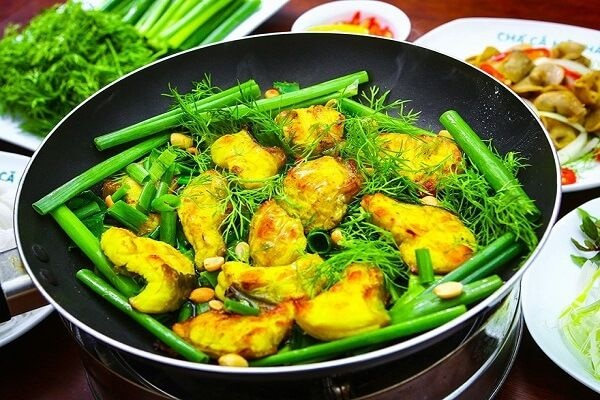 Sizzling Hanoi Cha Ca La Vong turmeric catfish with fresh dill and green onions in a pan