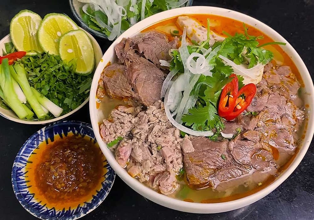 Rich and spicy Bun Bo Hue royal beef noodle soup with chili oil and fresh herbs