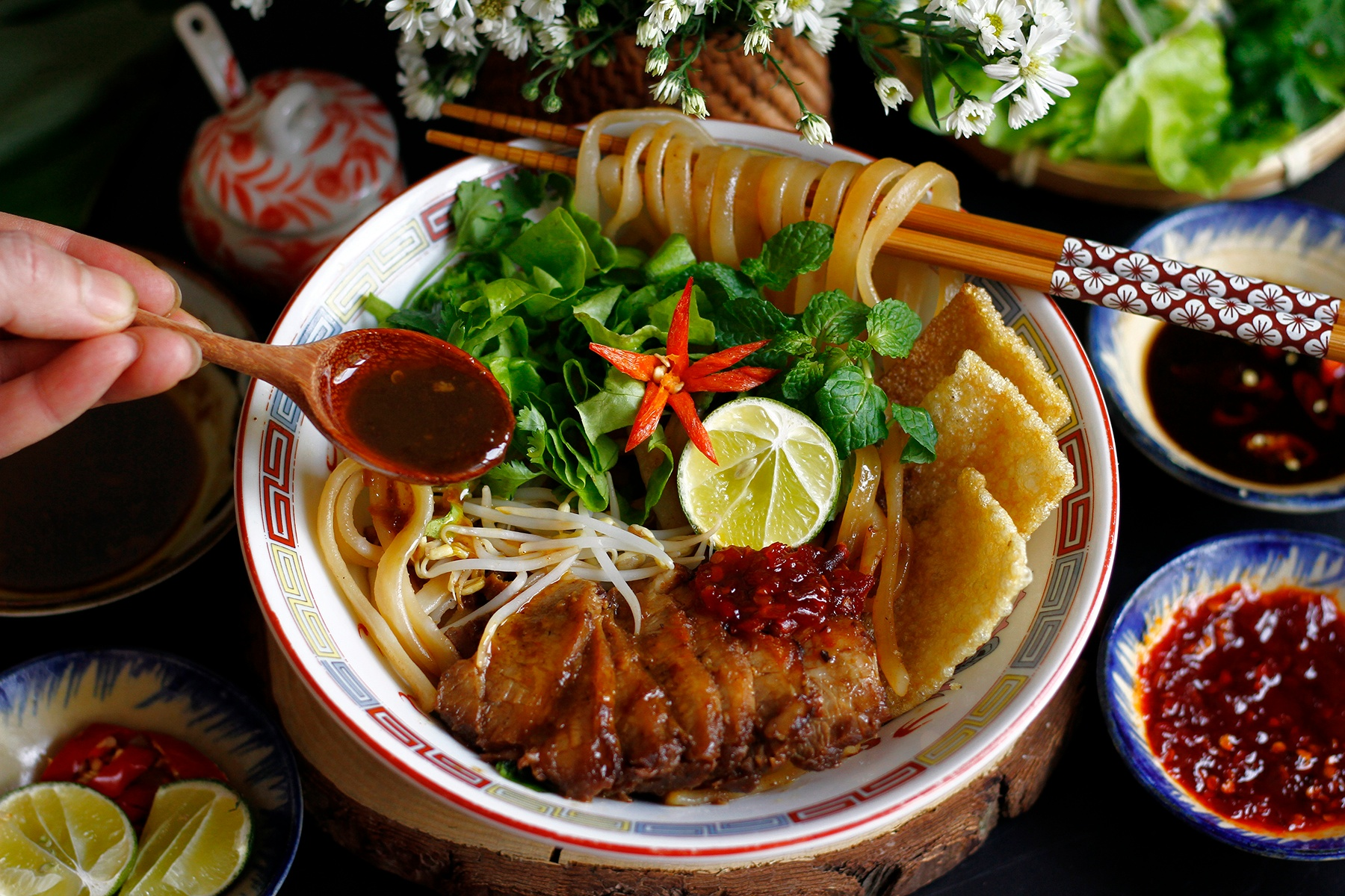 Traditional Hoi An Cao Lau noodles topped with braised pork, crispy rice crackers, and herbs
