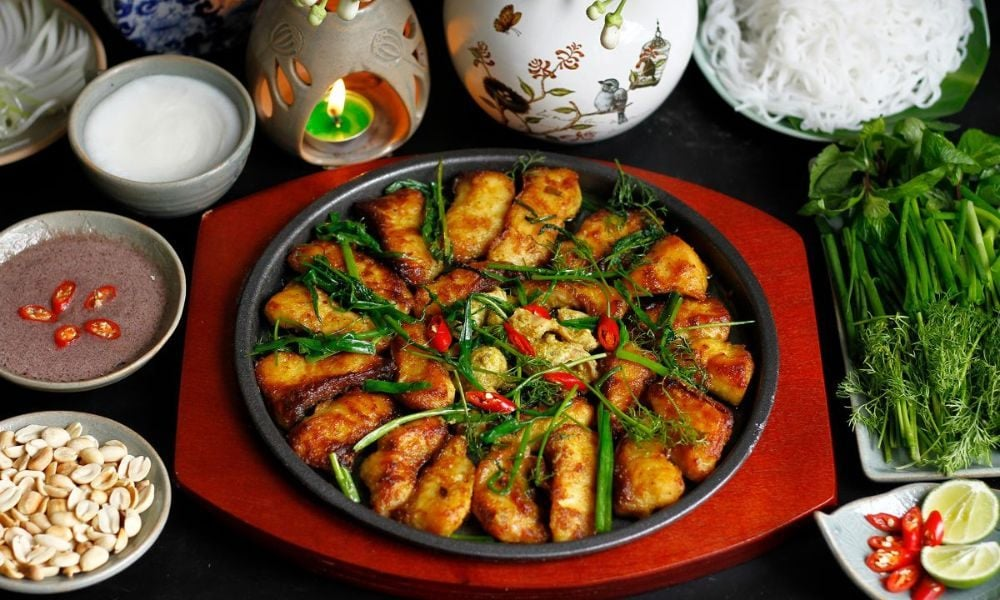Sizzling Hanoi Cha Ca La Vong turmeric catfish with fresh dill and green onions in a pan