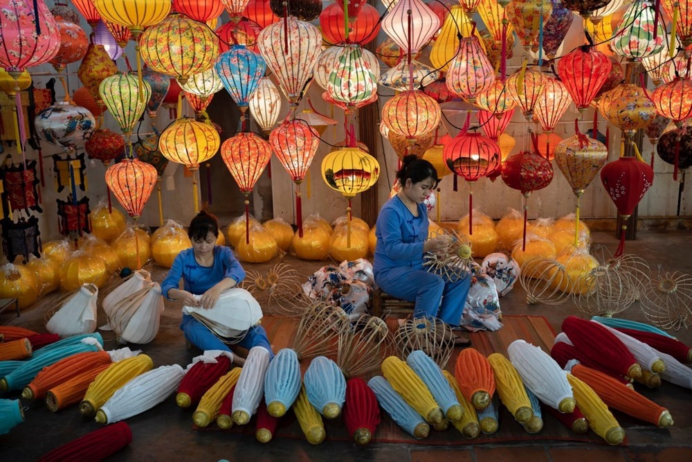 Local artisan women crafting colorful traditional silk lanterns inside a heritage workshop in Hoi An