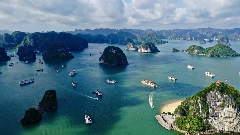Aerial drone view of emerald waters, limestone islands, and luxury cruise ships in Ha Long Bay Vietnam
