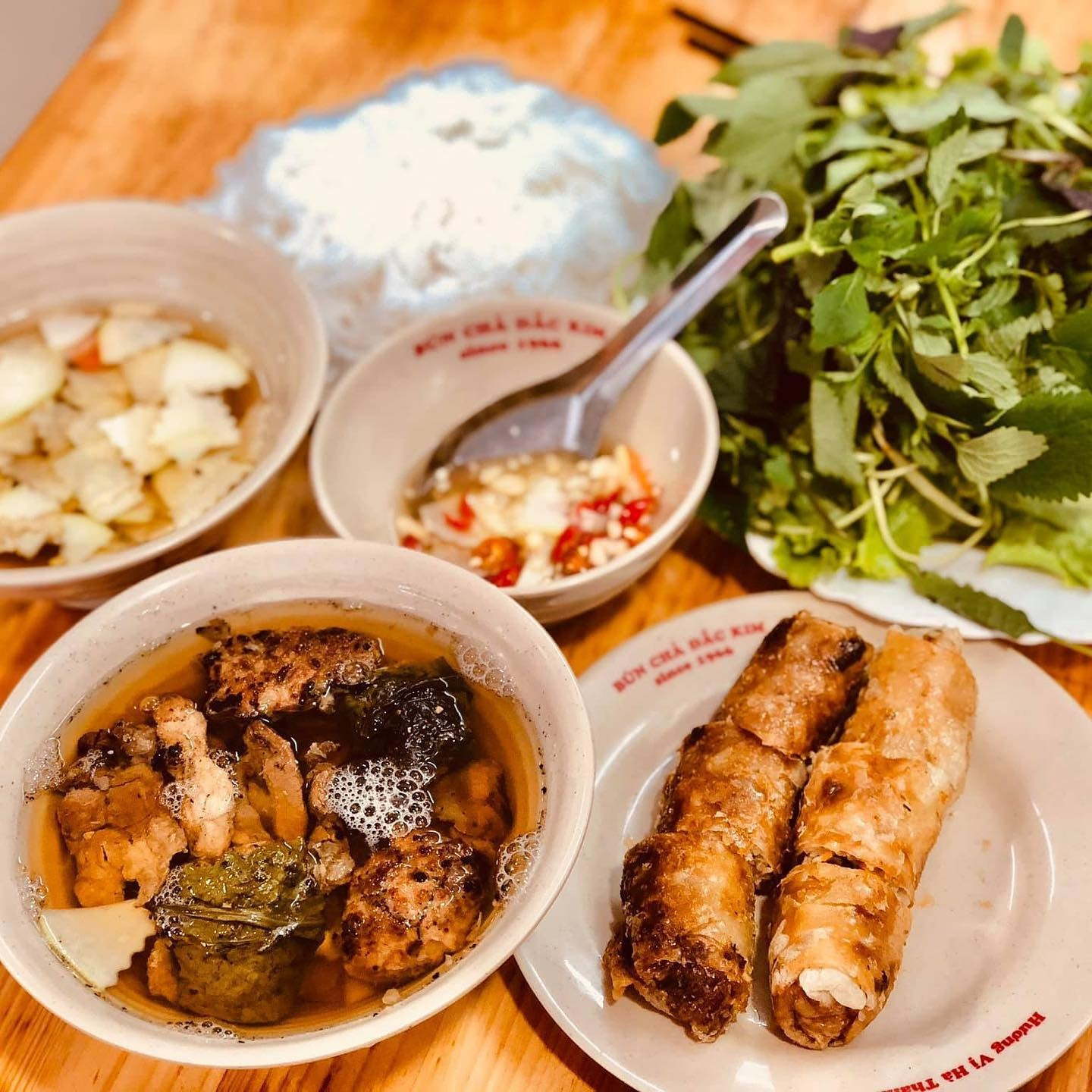 Traditional Hanoi Bun Cha set with charcoal grilled pork patties and fried spring rolls