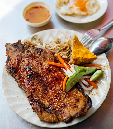 Saigon broken rice topped with a large grilled pork chop and egg loaf