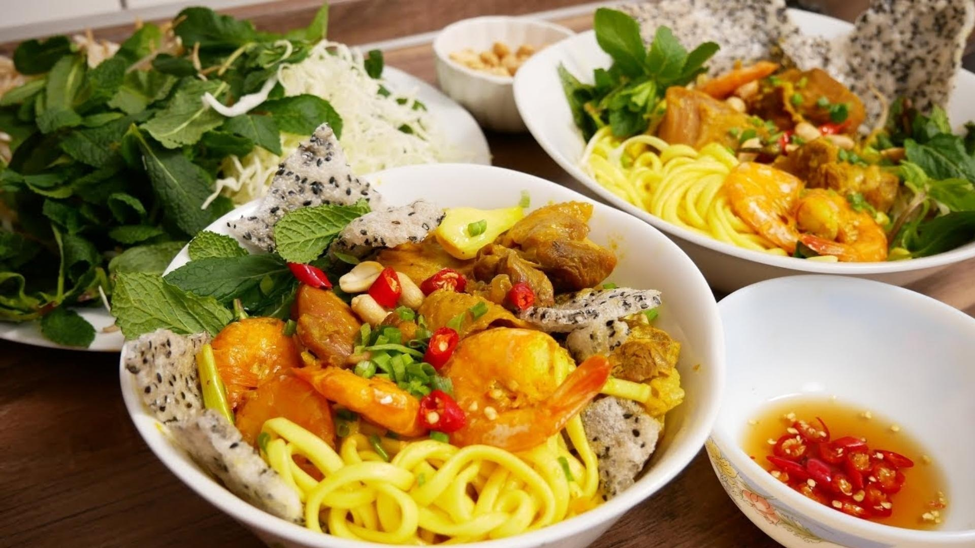 Bowls of Central Vietnam Mi Quang turmeric noodles topped with shrimp and rice crackers