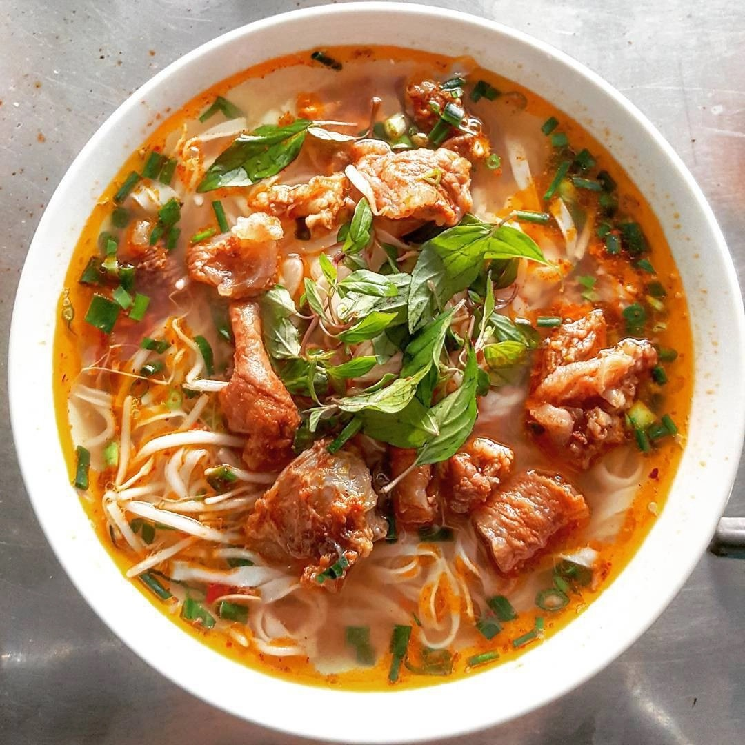 Bowl of rich red wine beef stew pho with fresh herbs