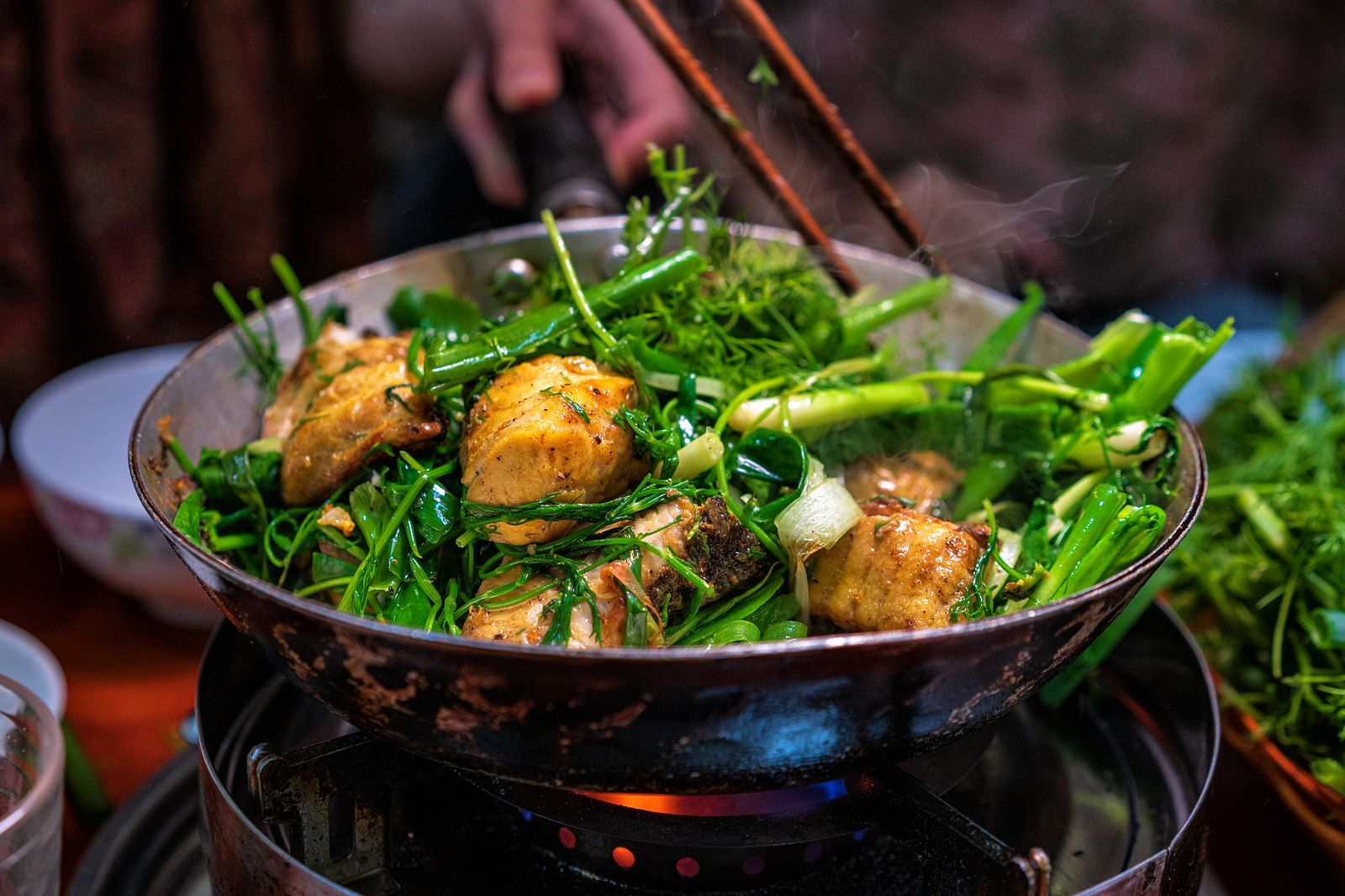 Sizzling turmeric fish with dill in a cast-iron skillet served with rice vermicelli