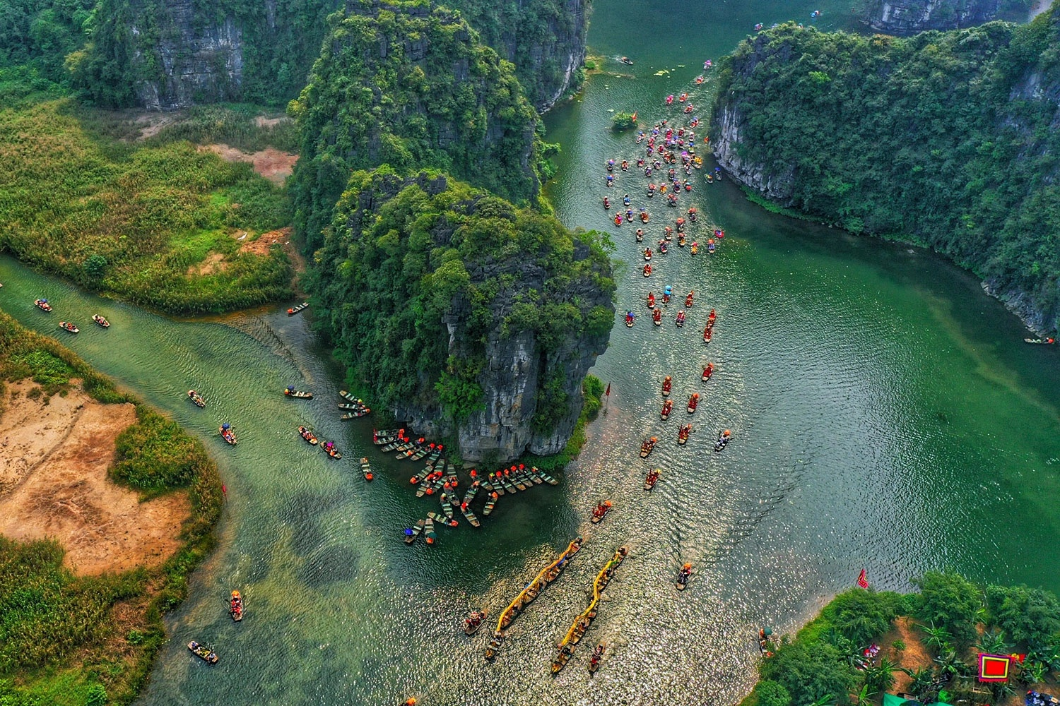 Aerial view of colorful dragon boat procession on Trang An river in Ninh Binh