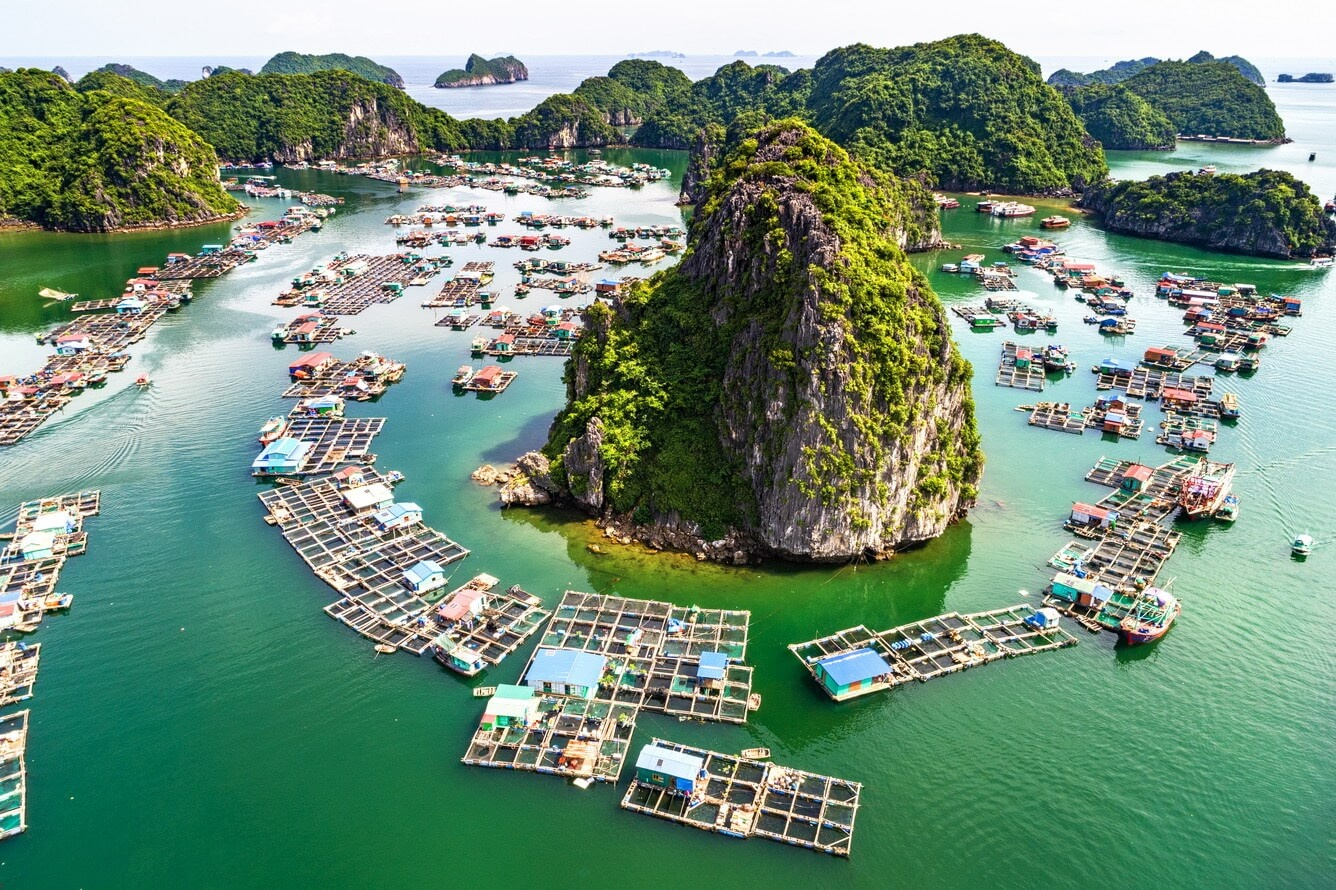 Aerial view of floating fishing village surrounded by karst islands in Lan Ha Bay