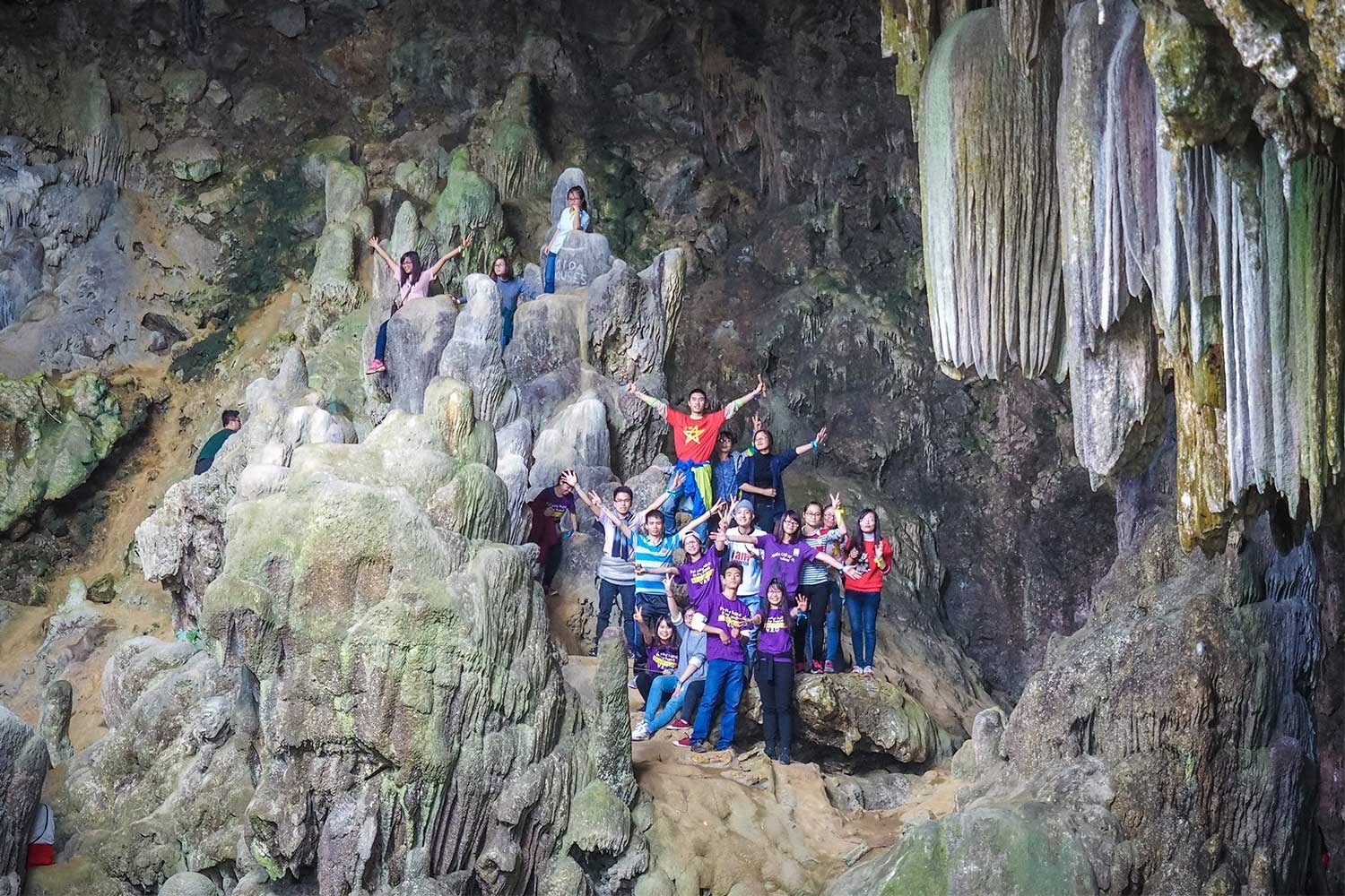 Travelers exploring limestone stalactites inside Chieu Cave in Mai Chau
